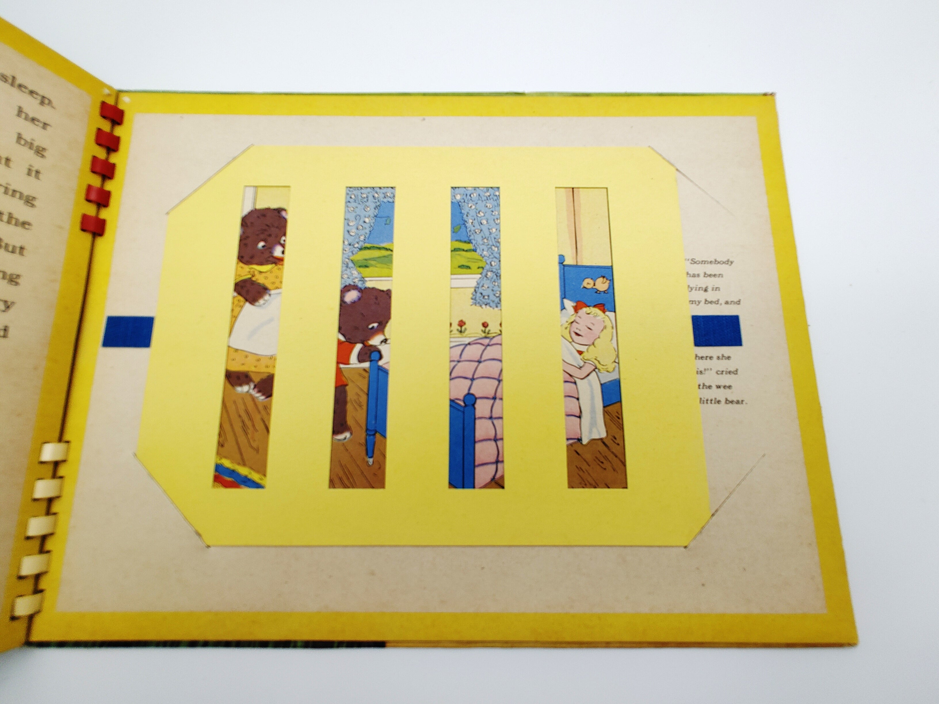 Slat moveable illustration of Goldilocks asleep in Baby Bear's bed from Emma McKean's Goldilocks and the Three Bears (1943)
